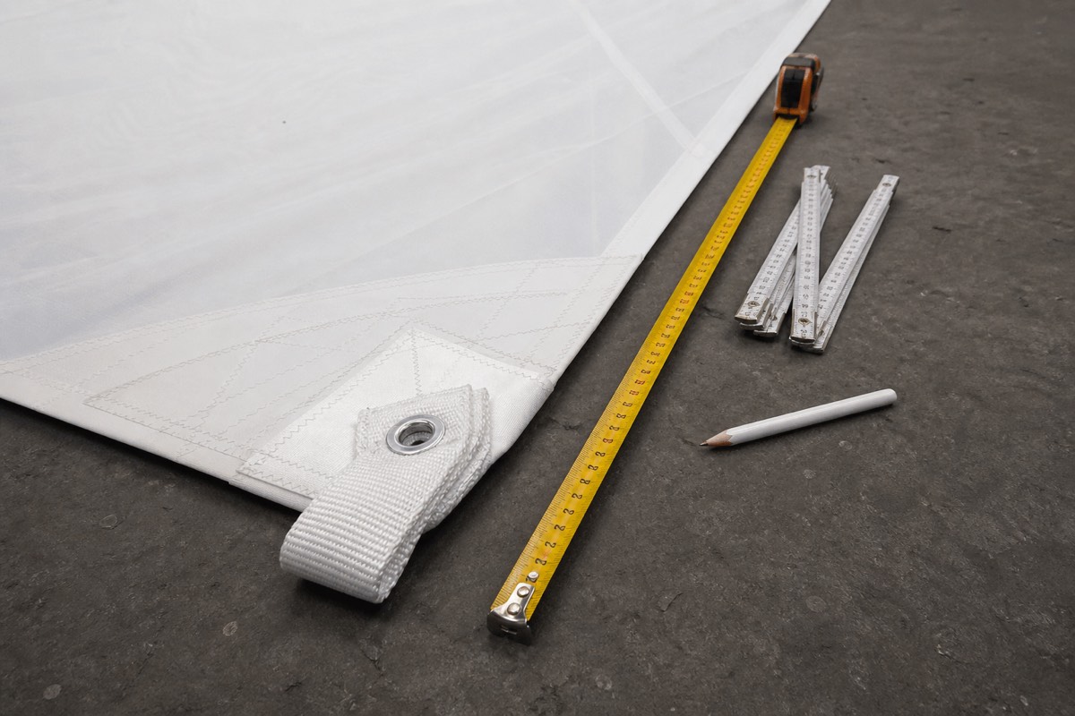 A long tape measure, folding rule and sailmaker pencil beside a sail head
