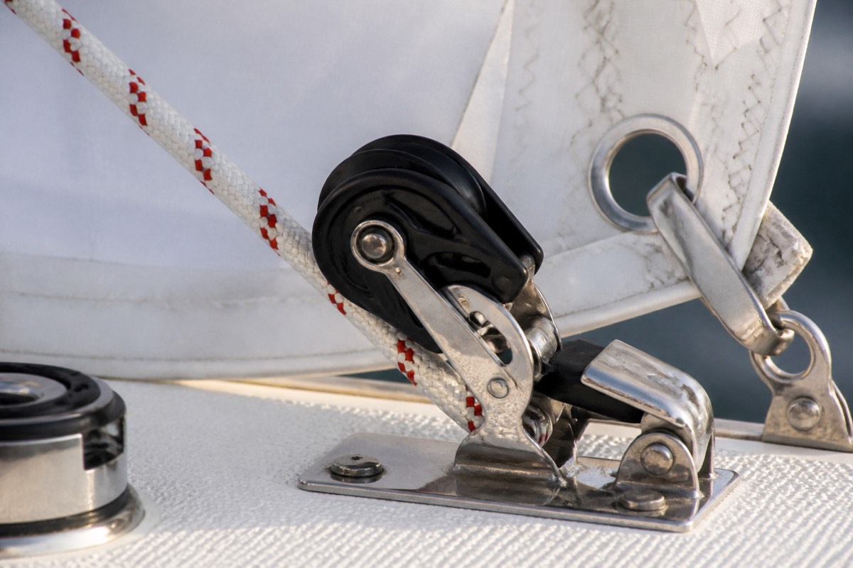 A reefing line, block and sail slide beside a stainless deck fitting
