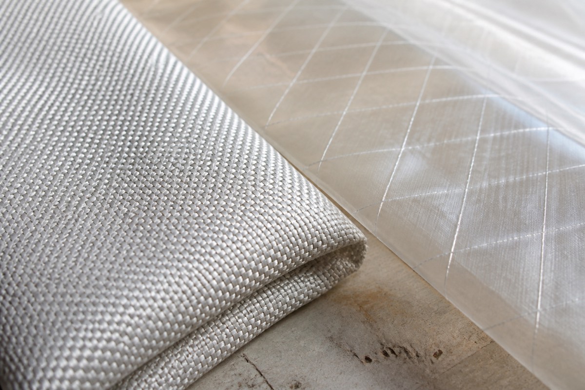 A close view of woven polyester cloth beside a translucent sail laminate